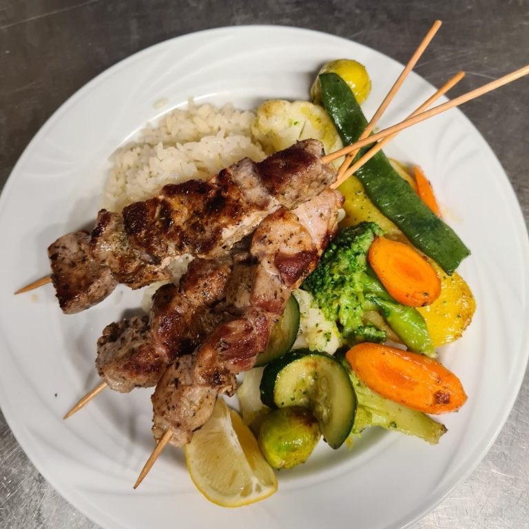 Griechische Küche Grillspieße mit Gemüse und Reis auf einem weißen Teller.